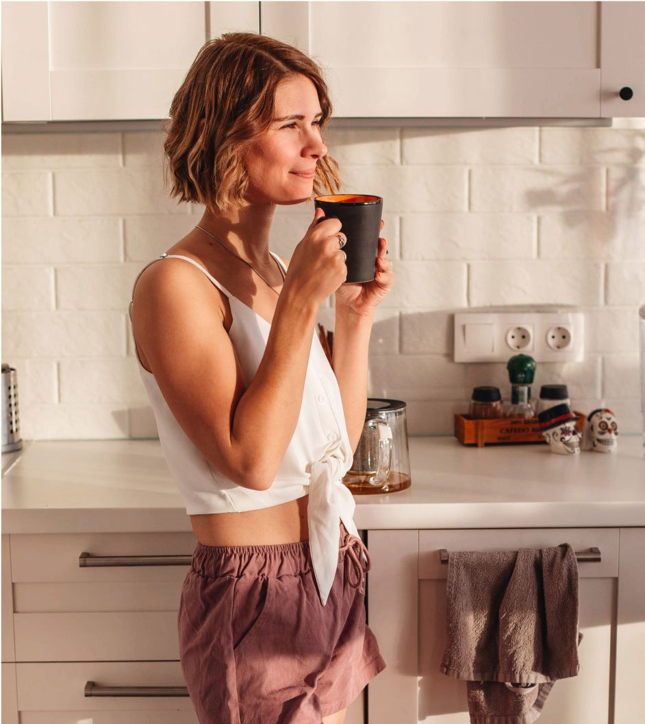 info-2 Woman Holding Cup Standing in the Kitchen
